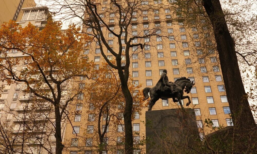 Looking out from the Park across 57th Street, the statue is seen in profile against a building.