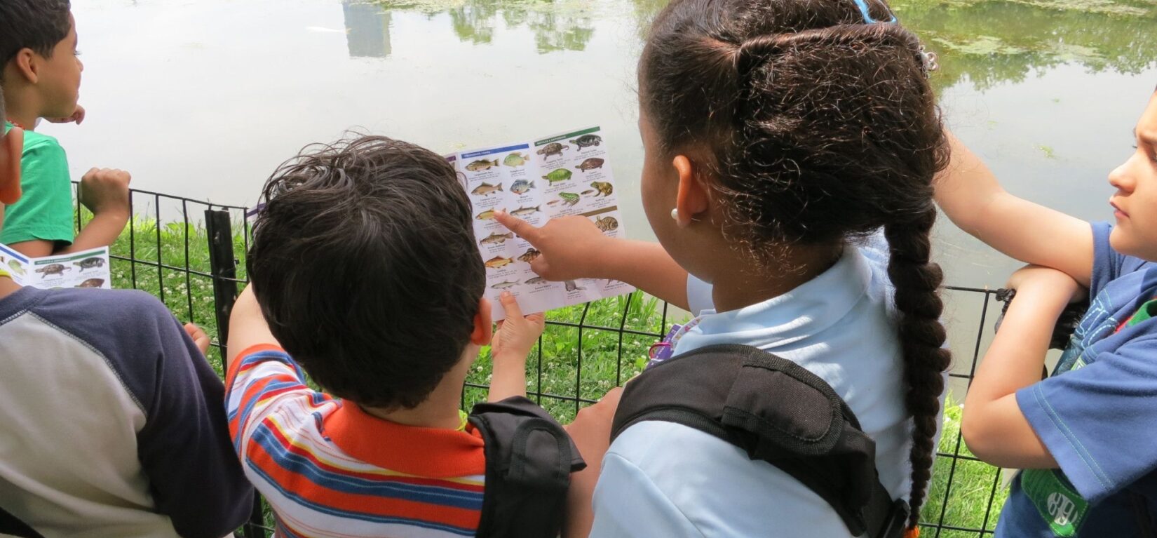 Children pointing at a Central Park discovery kit page