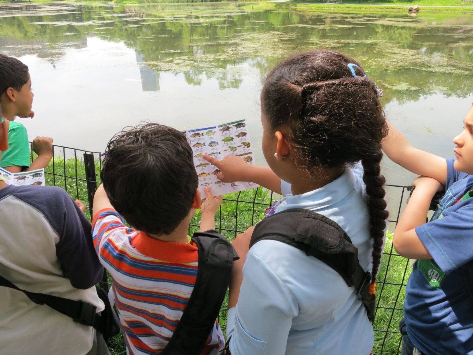 Children pointing at a Central Park discovery kit page