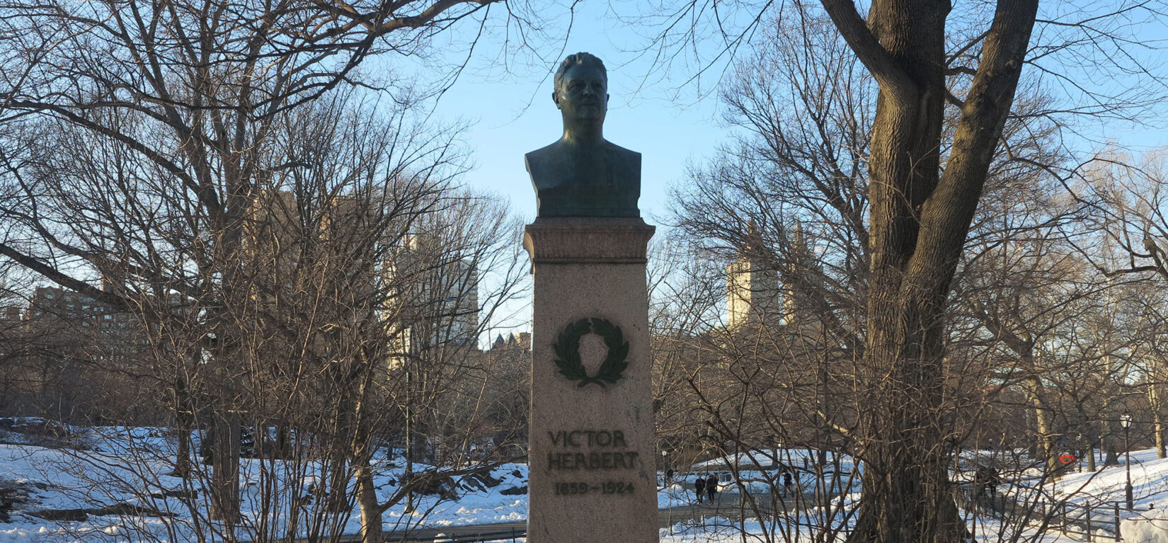 The bust of Victor Herbert sits on a tall pedestal amid a wintery landscape