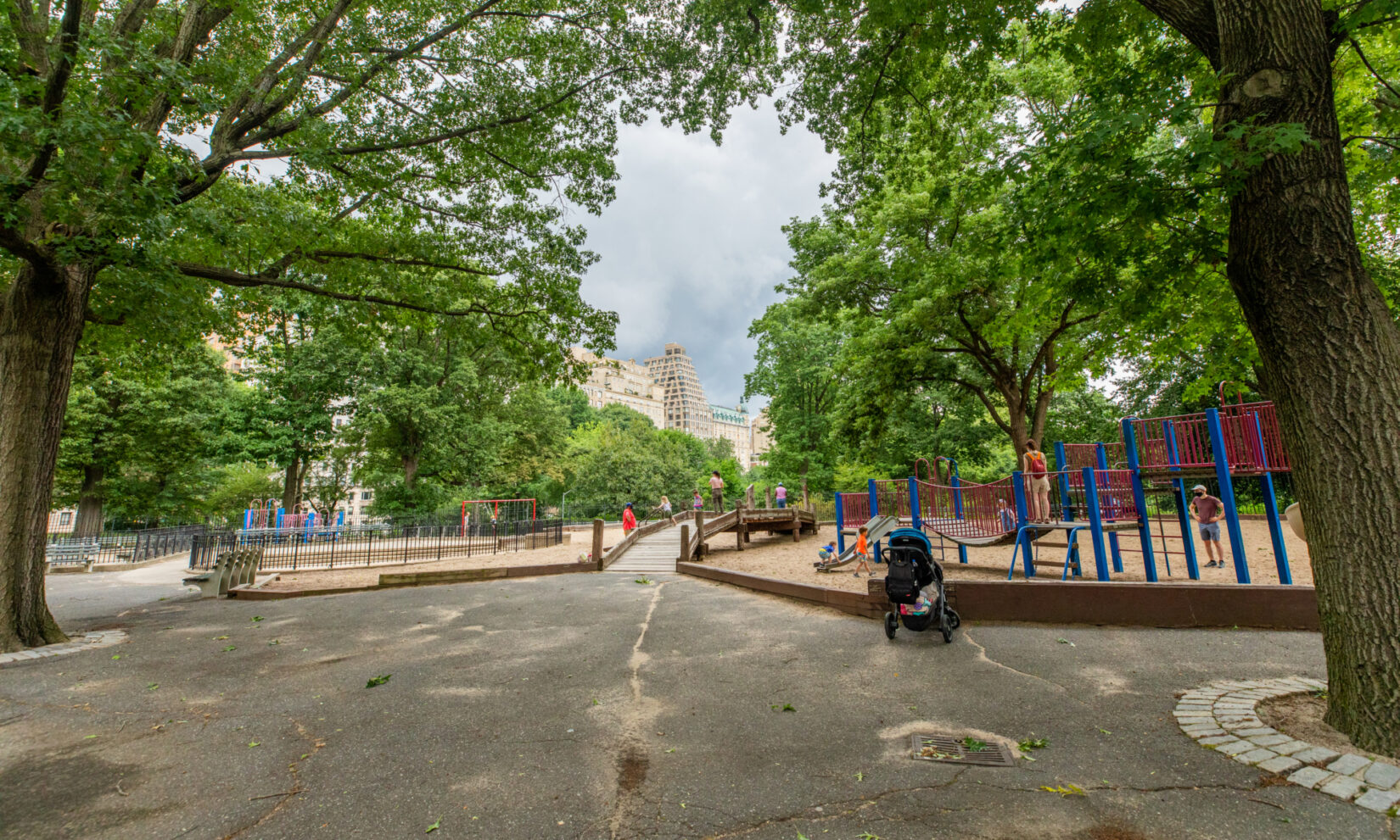 Looking down the Park path and across the rustic footbridge of the playground in summer.