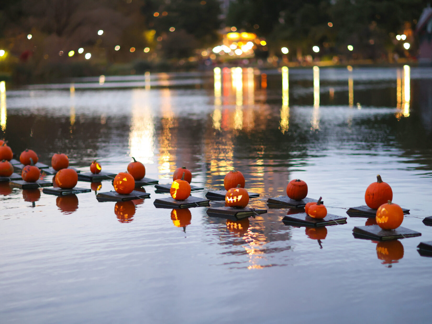 Jack-o'-lanterns floating on the waters of the Harlem Meer at dusk.