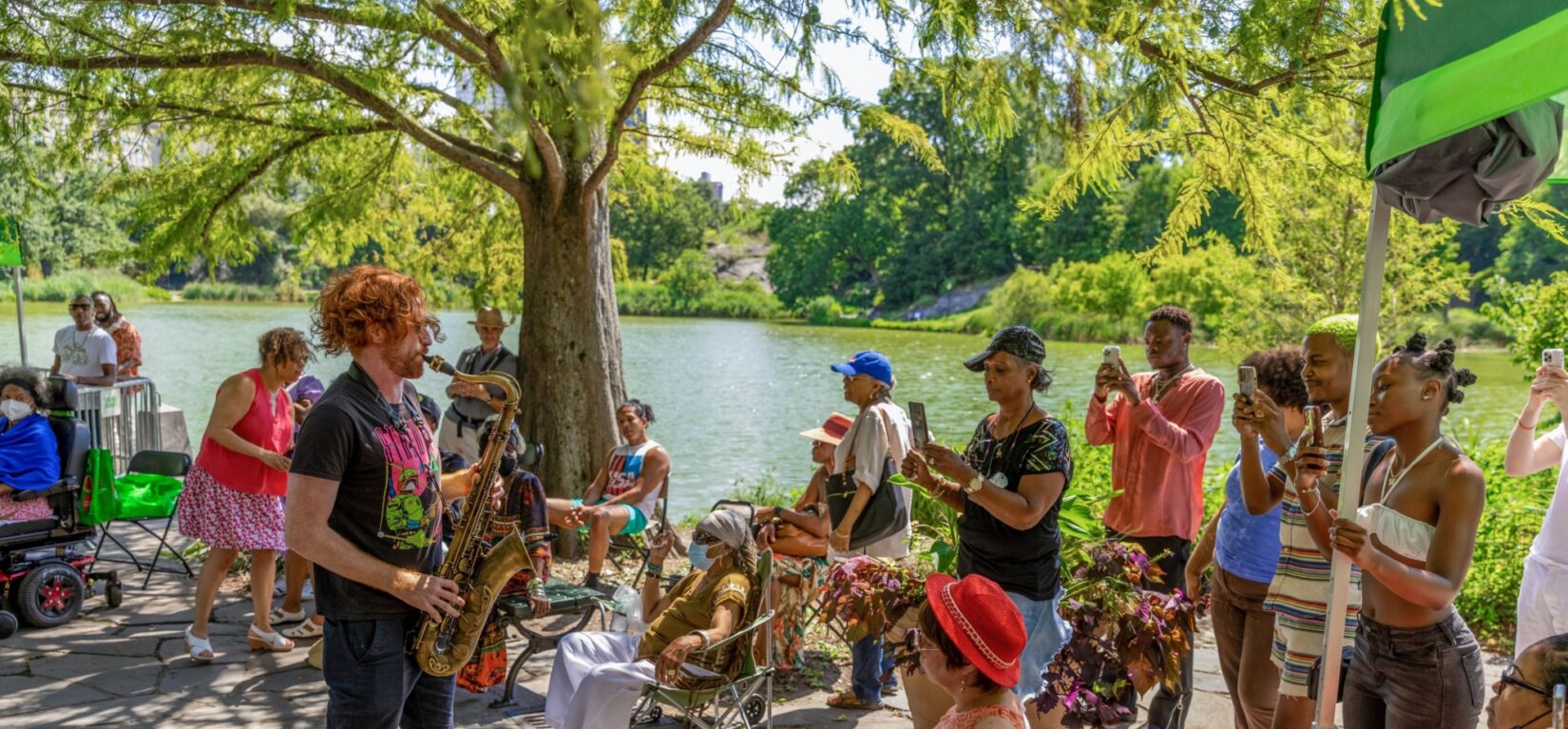 A saxophone player at the Harlem Meer Performance Festival, surrounded by audience in Central Park