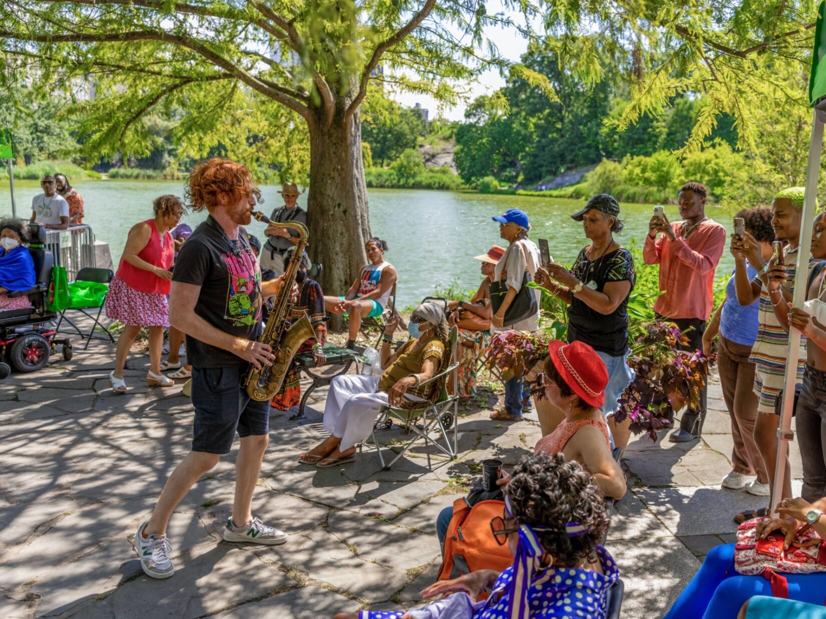 A saxophone player at the Harlem Meer Performance Festival, surrounded by audience in Central Park