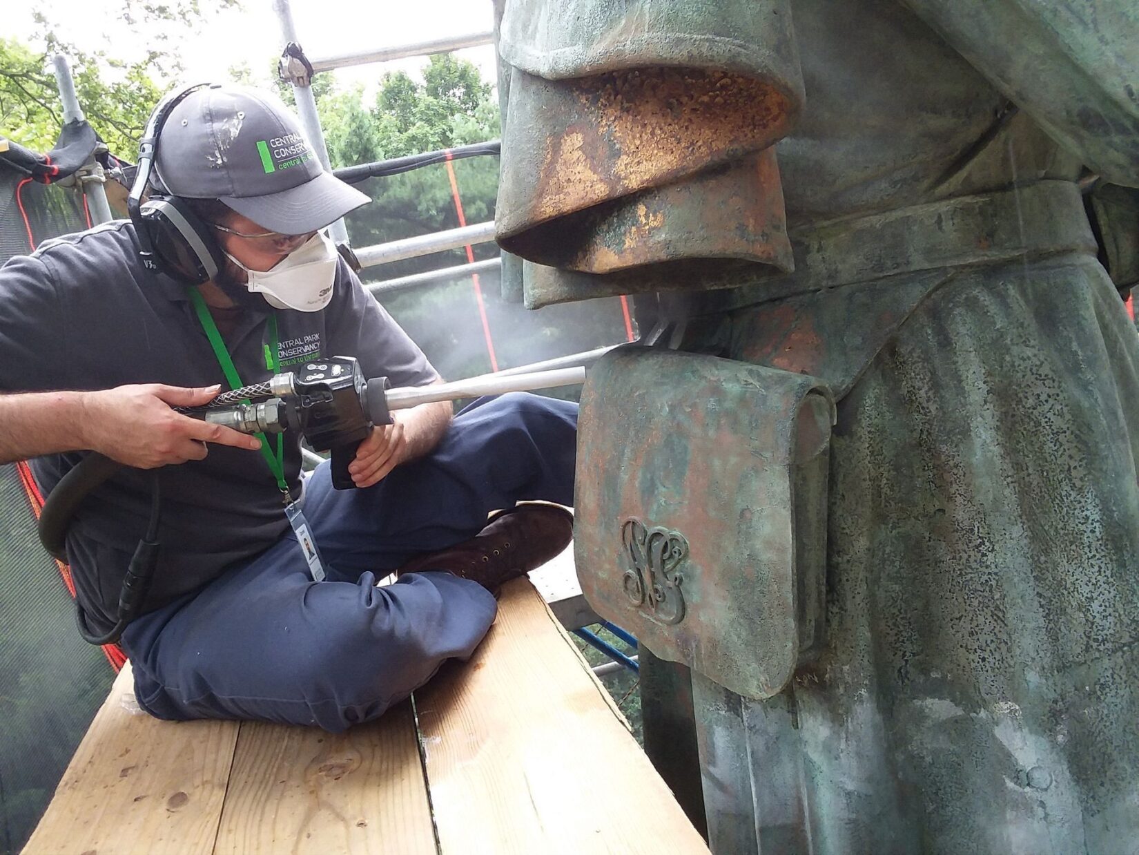 A worker power cleans the bronze statue.