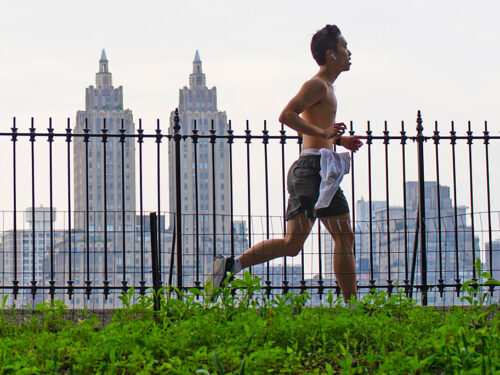 A shirtless runner silhouetted against the fencing of the reservoir