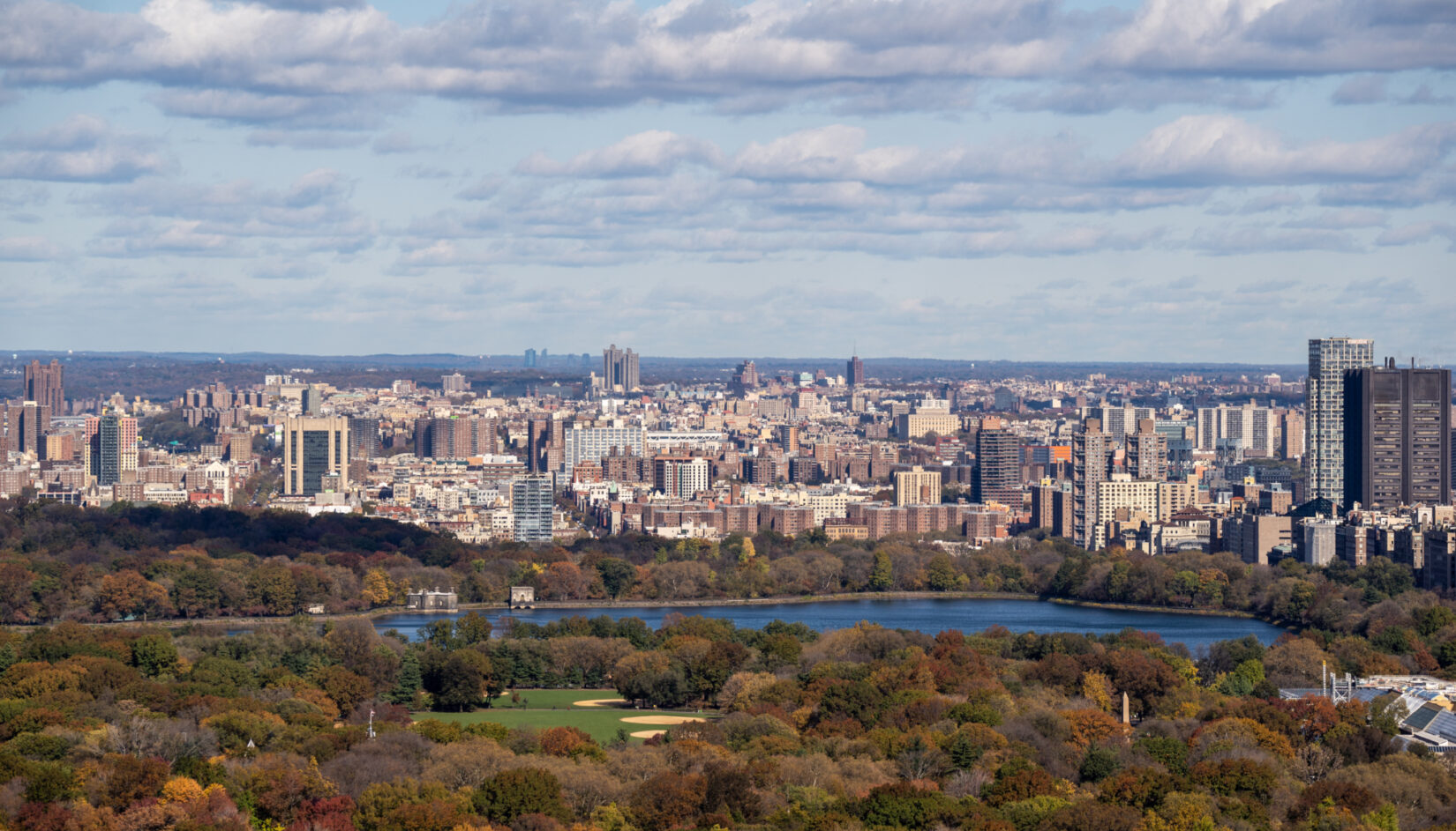 An aerial view looking north from the end of the Great Lawn, past the Reservoir, to the skyline of Harlem in the background