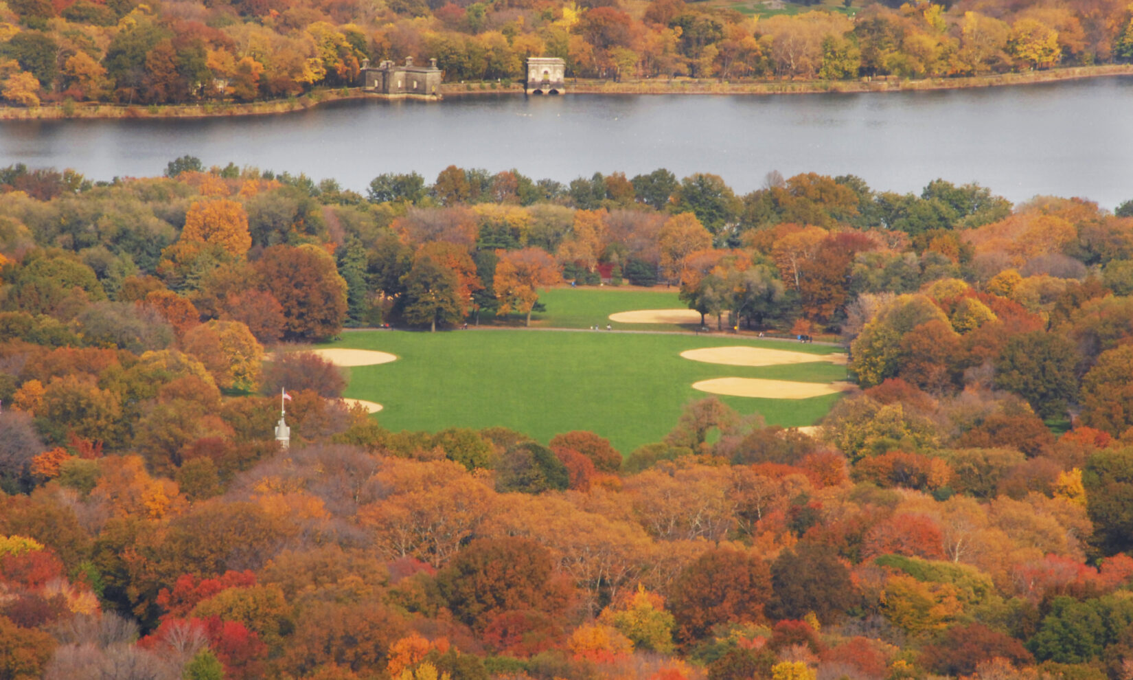 An aerial view of the Lawn in autumn, puncuated by baseball diamonds, with the waters of the Reservoir at the top of the frame.