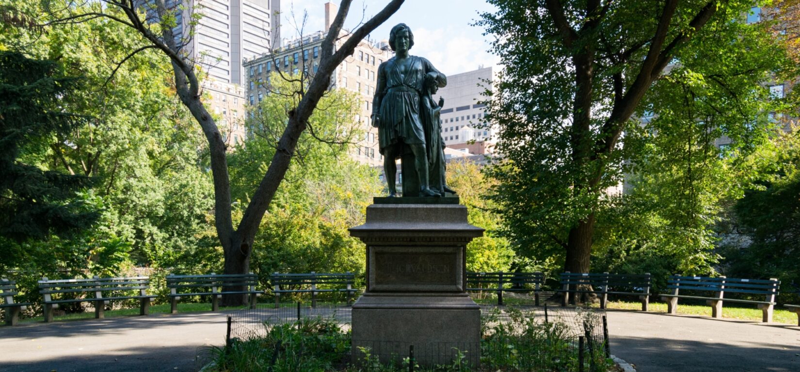 The statue framed by trees with the skyline in the background