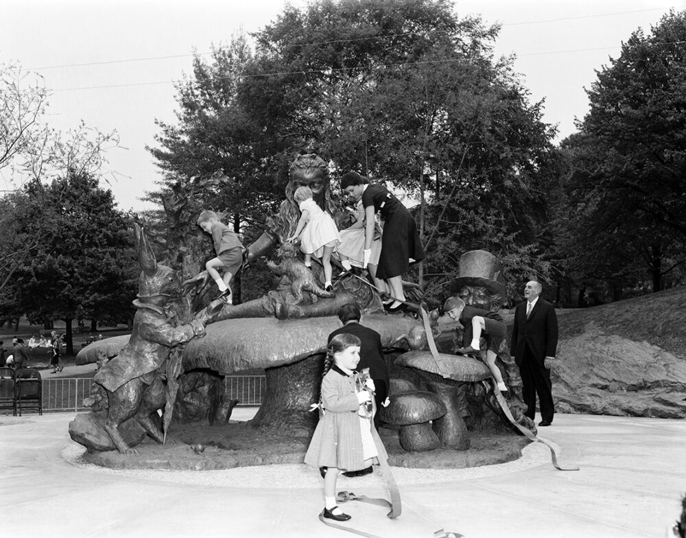 Robert Moses stands to one side, enjoying the children clamboring over the statue