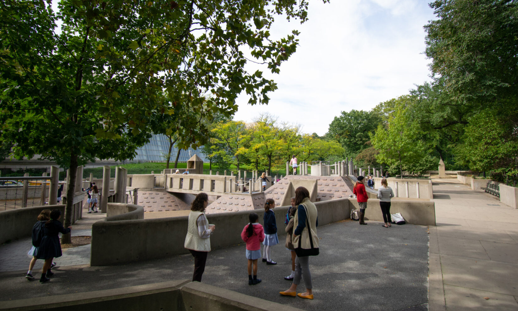 Families enjoying the playground with the enclosure of the Temple of Dendur in the background.