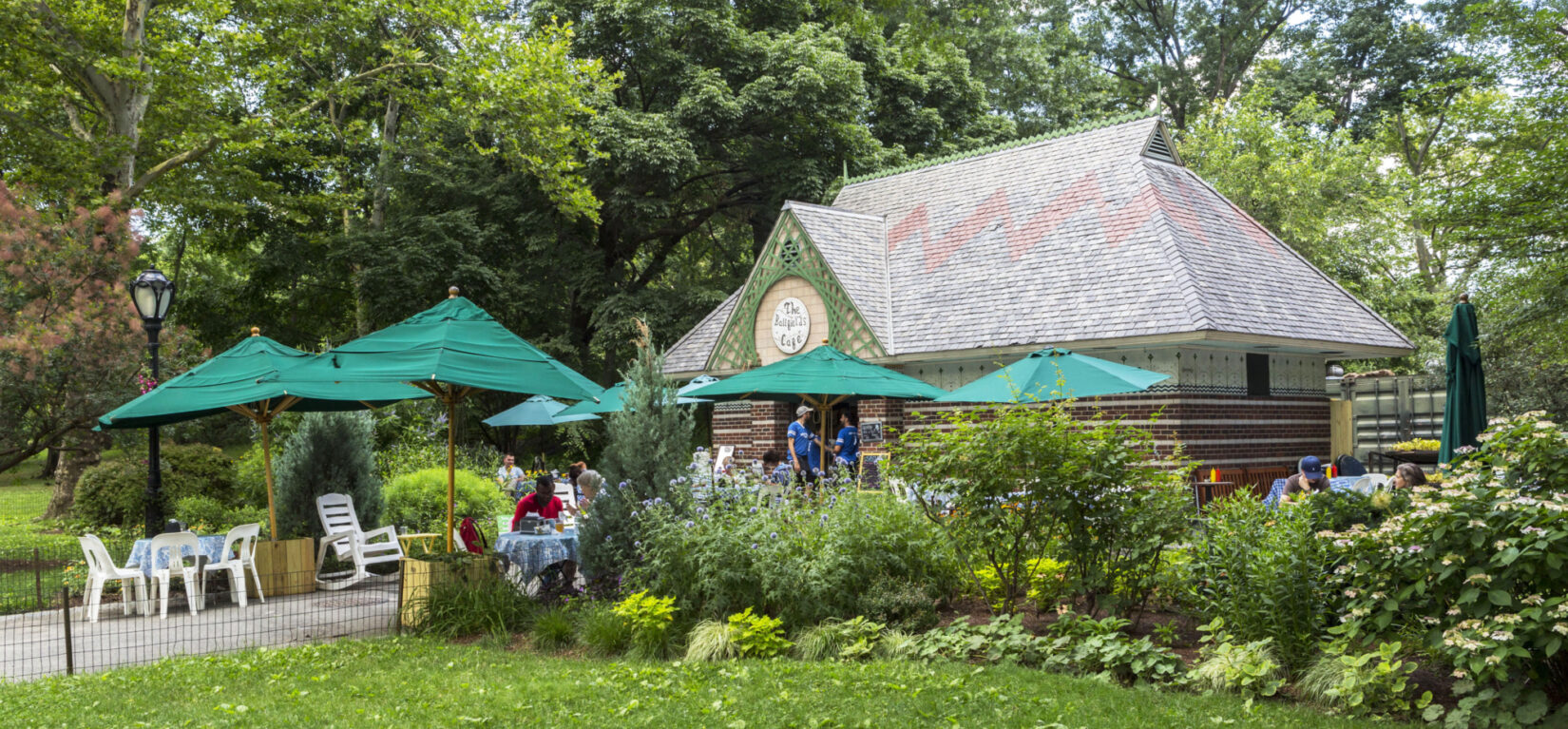 People enjoying cafe fare under green umbrellas in the outdoor dining area of the cafe