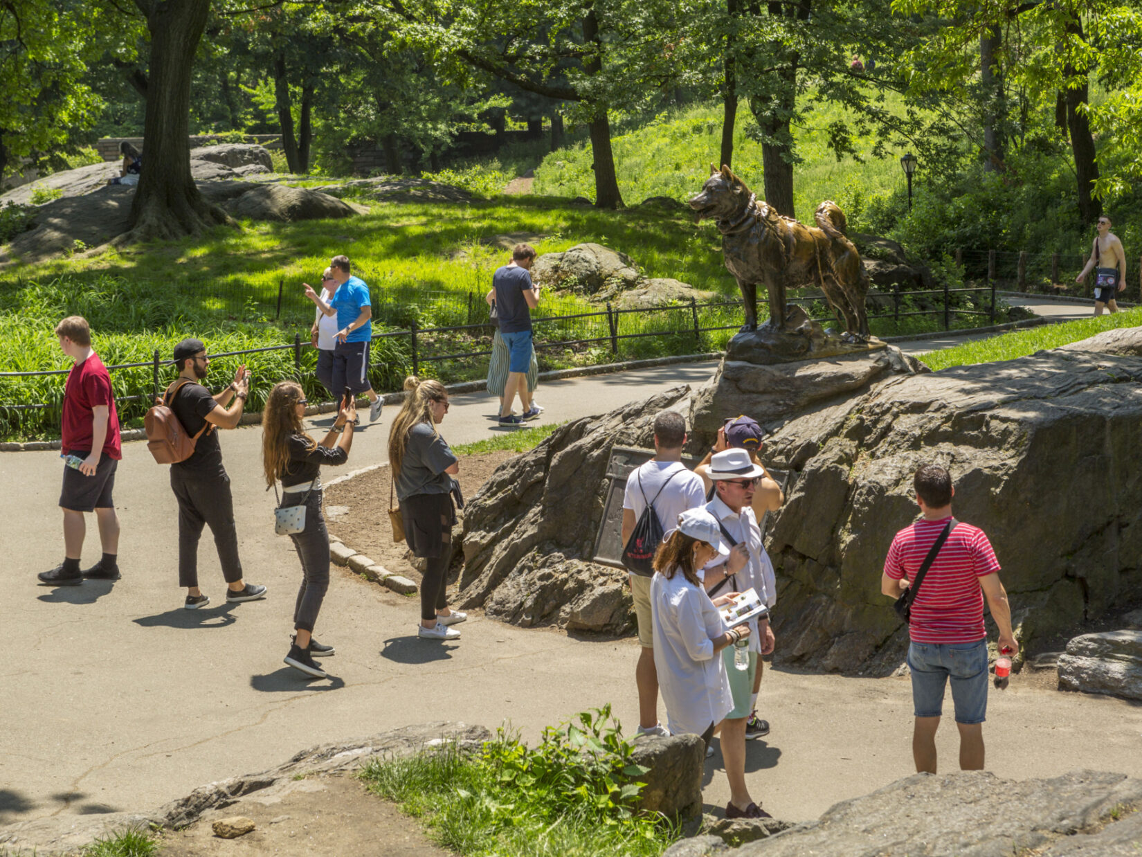 Visitors admire and photograph the statue of Balto on a sunny day