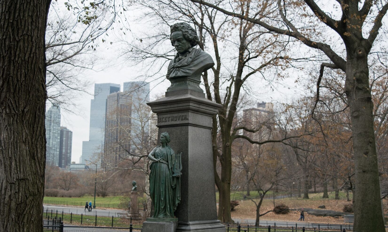 The bust and plinth against a backdrop of barren winter trees and gray sky