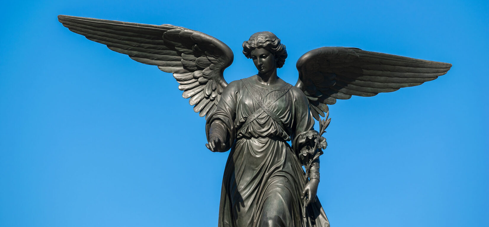 A close-up view of Our Lady of the Water silhouetted by a blue sky