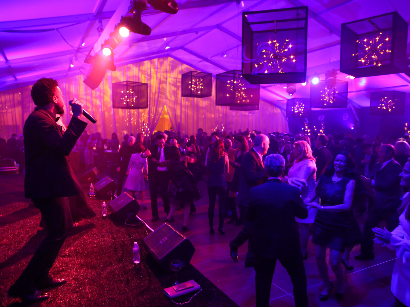 A crowd dances in a tent to a performance on stage