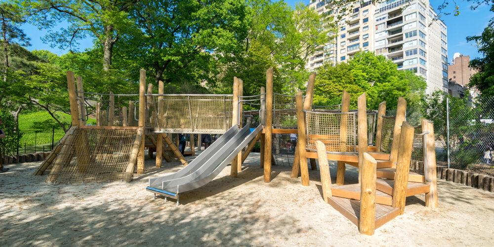 Play apparatus made of wood and rope on a sandy lot, shaded by trees