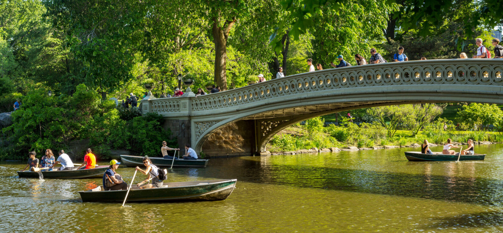 Boaters row beneath the span of the Bow Bridge