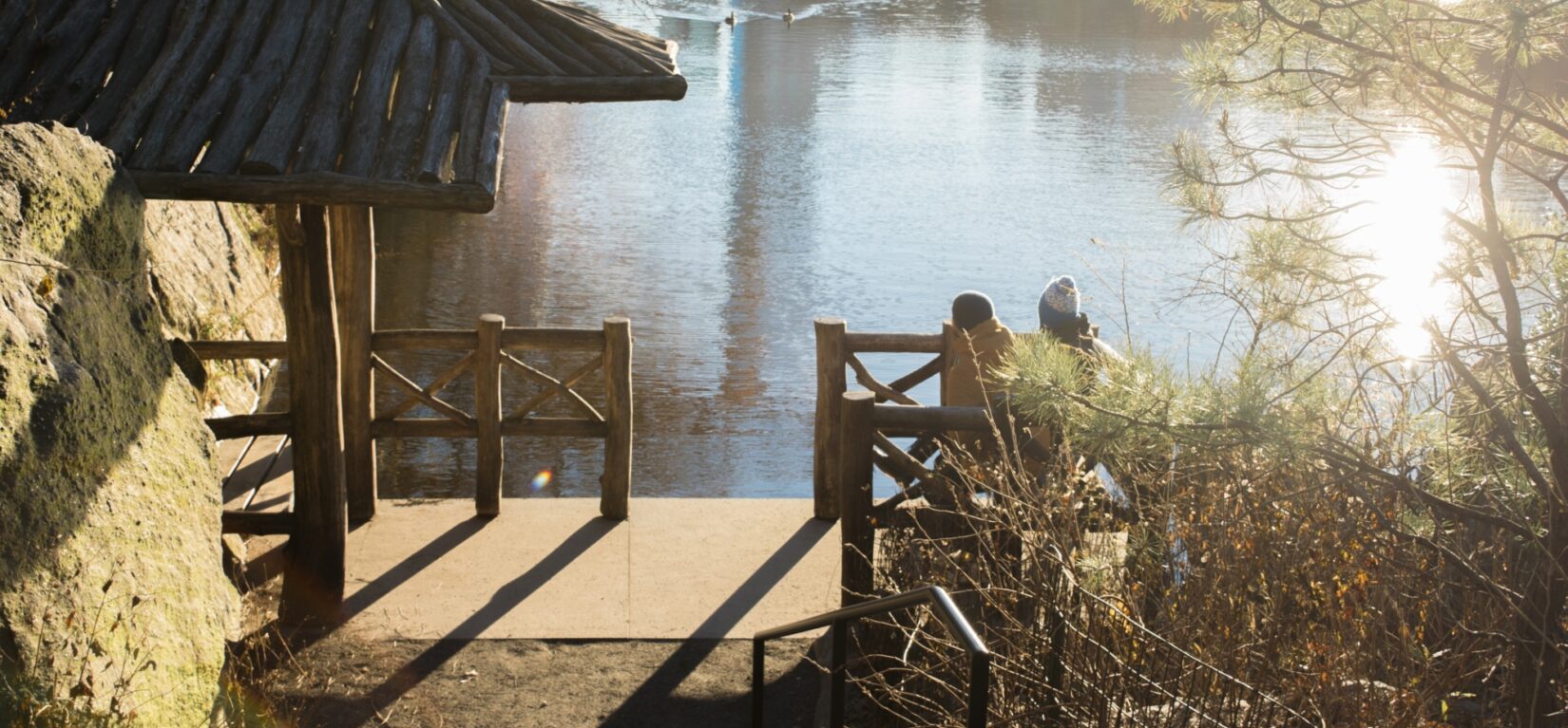 Two people enjoy a view of the Lake from a bench on the Chambers Boat Landing