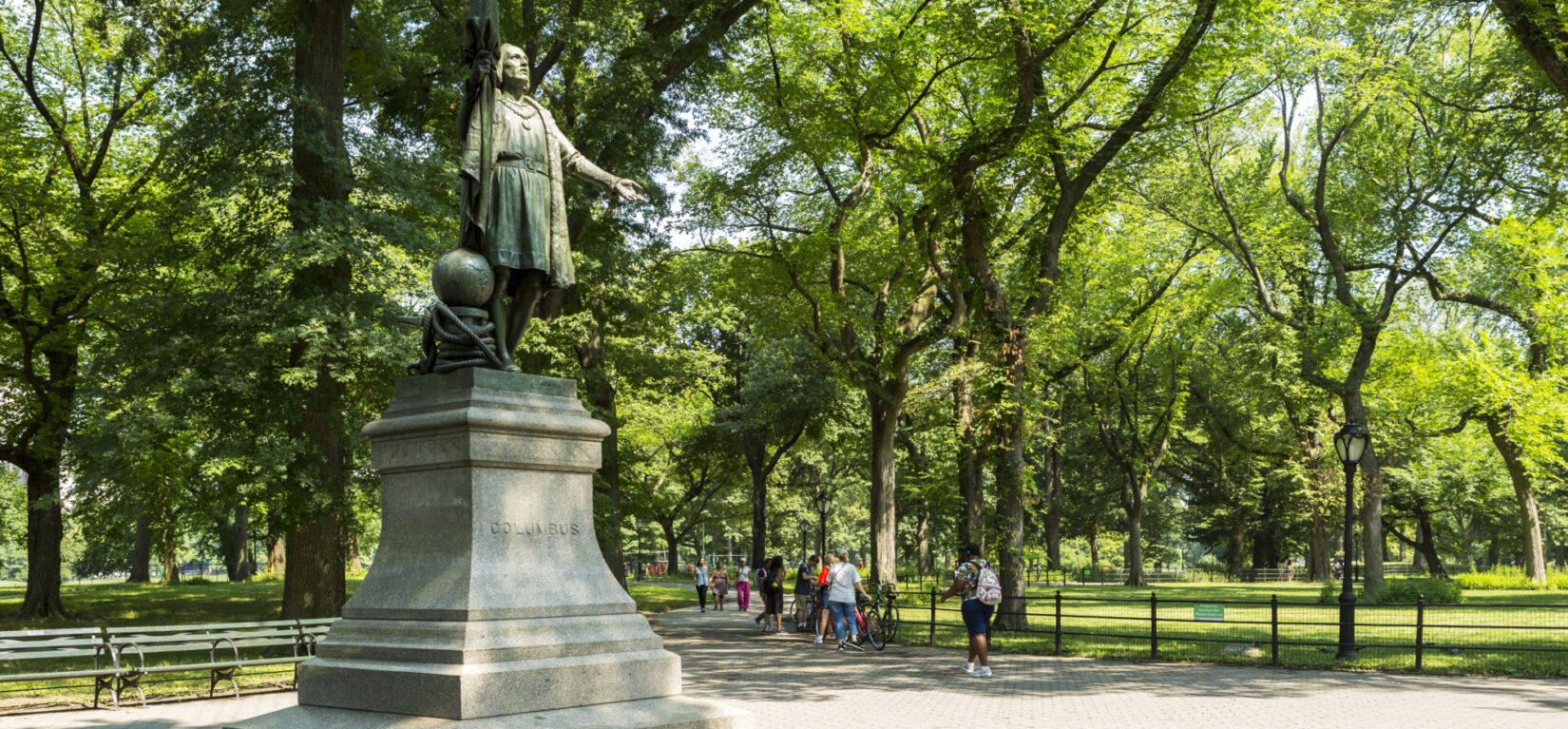 Visitors follow the path leading from the statue on a summer day