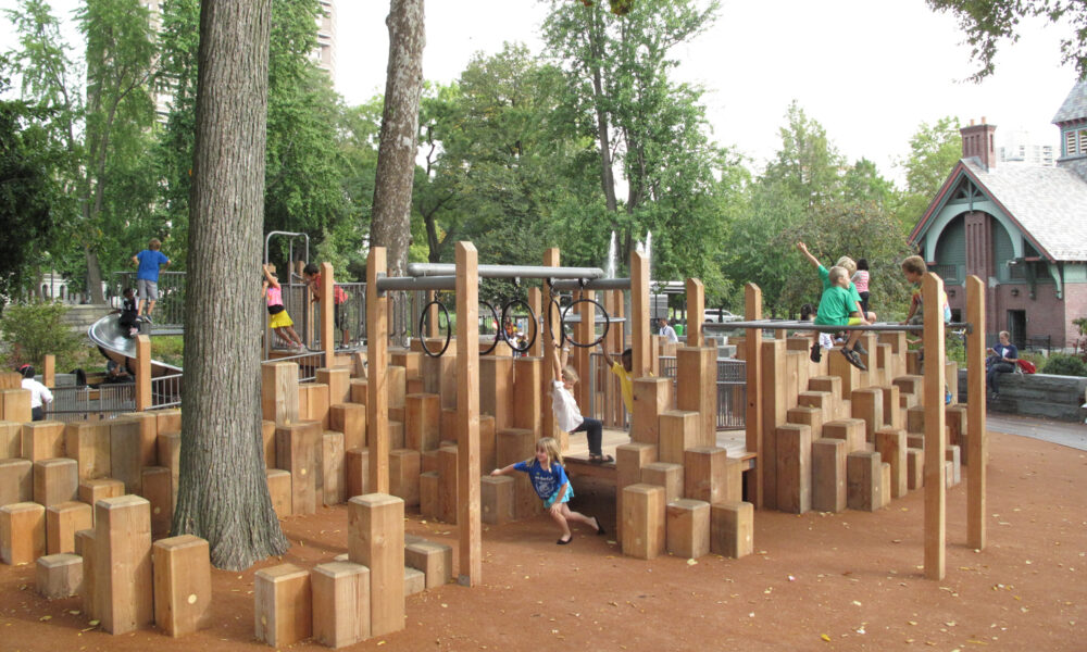 Children climbing the wood pilings and climbing rings of the playground.