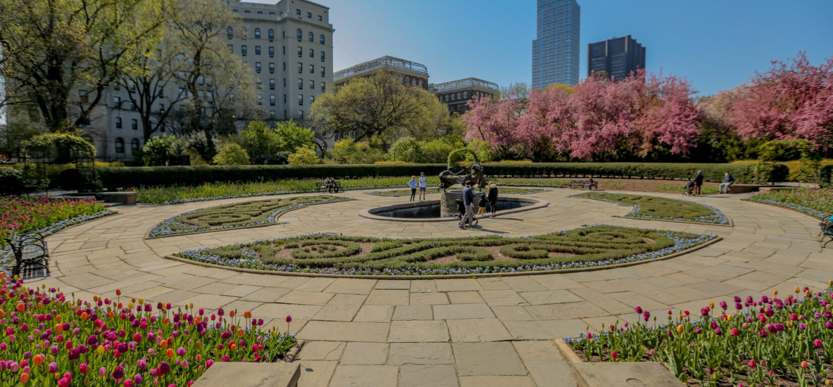 A section of Conservatory Garden pictured under a cloudless blue sky, showing the early blooms of spring.