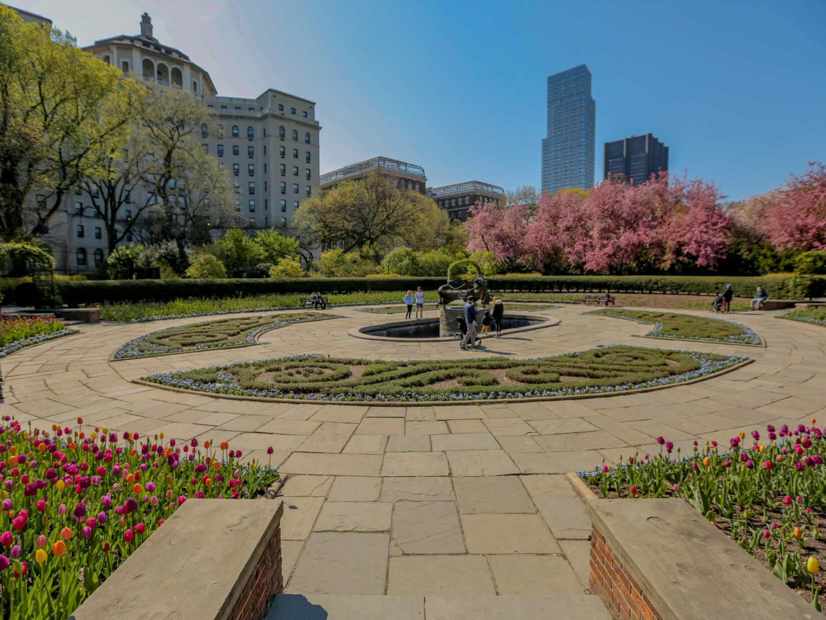 A section of Conservatory Garden pictured under a cloudless blue sky, showing the early blooms of spring.