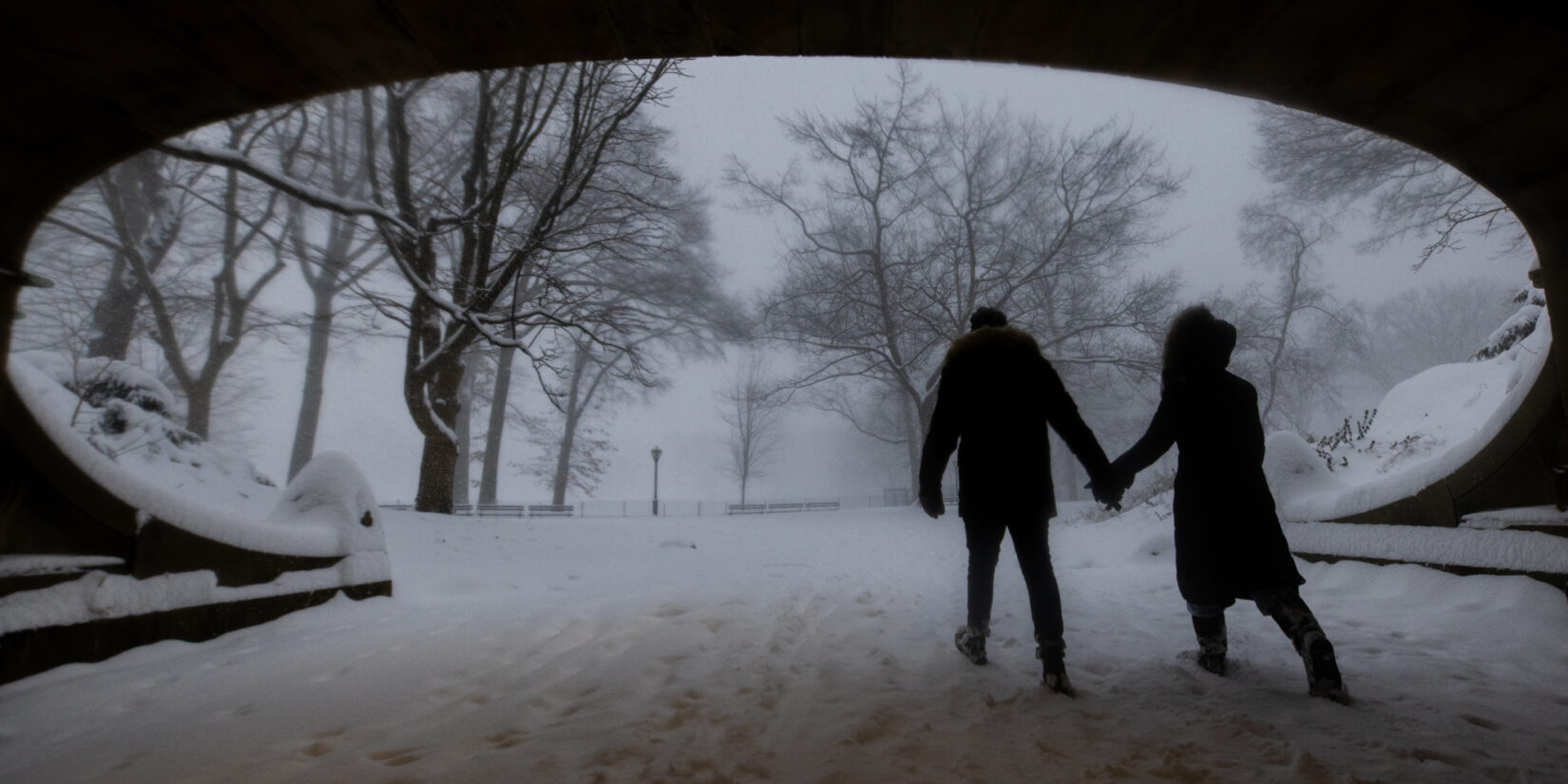 A couple trudge beneath Dalehead Arch in a snowstorm