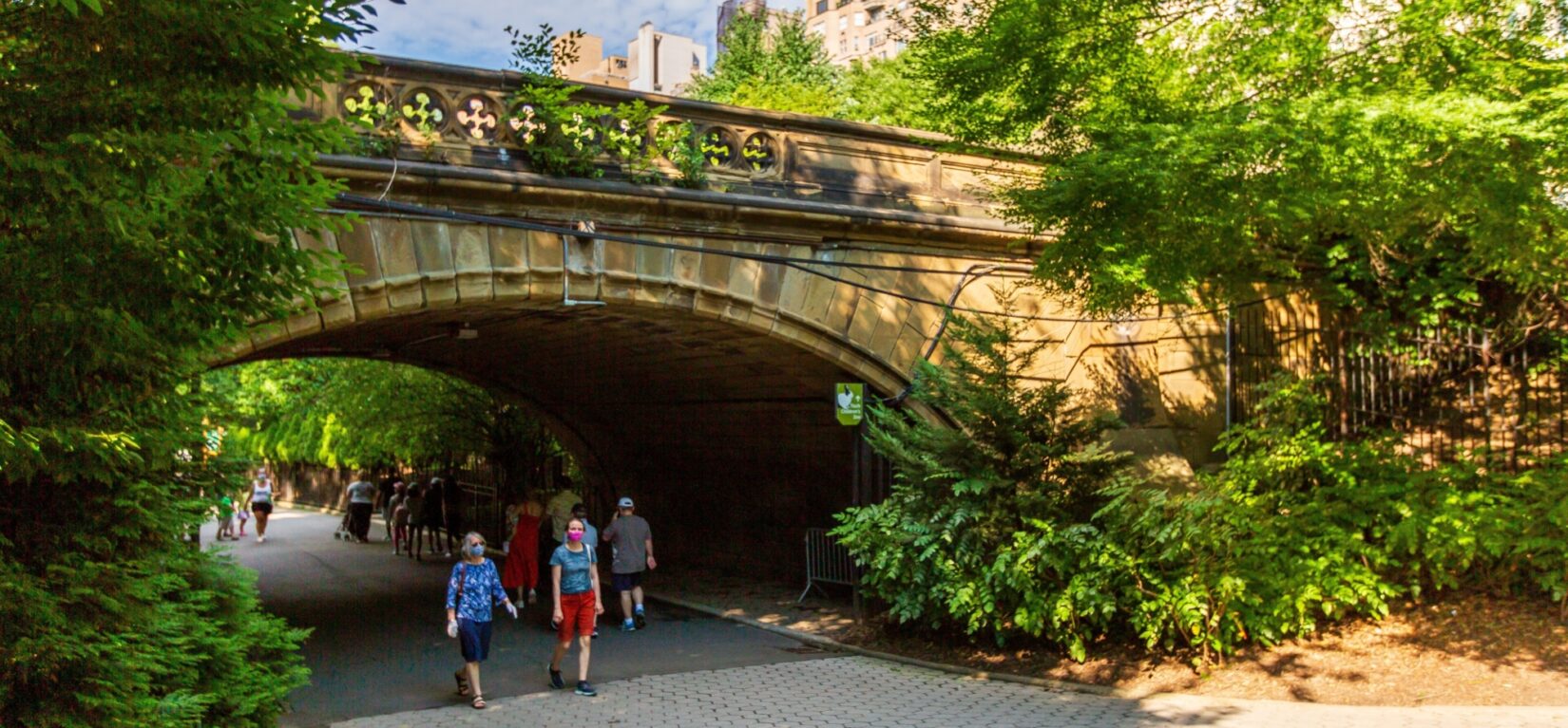 Visitors strolling beneath the Denesmouth Arch in summer