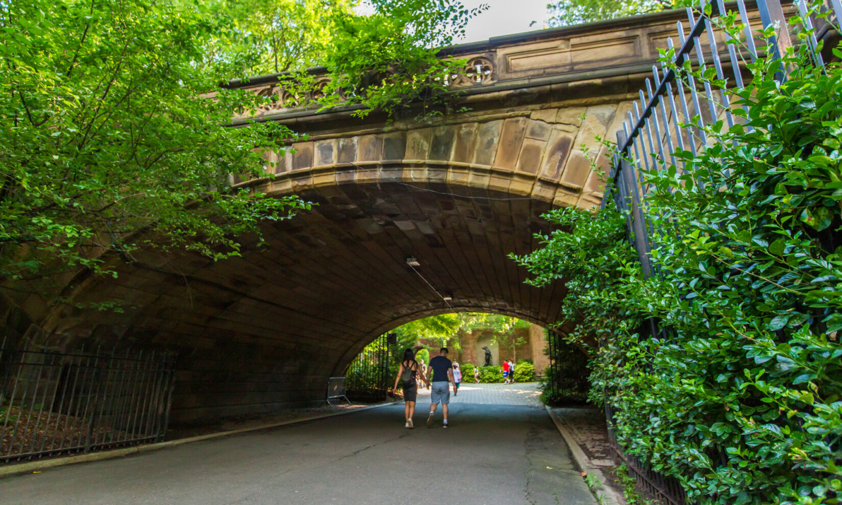 A couple ambles under the arch toward Central Park Zoo