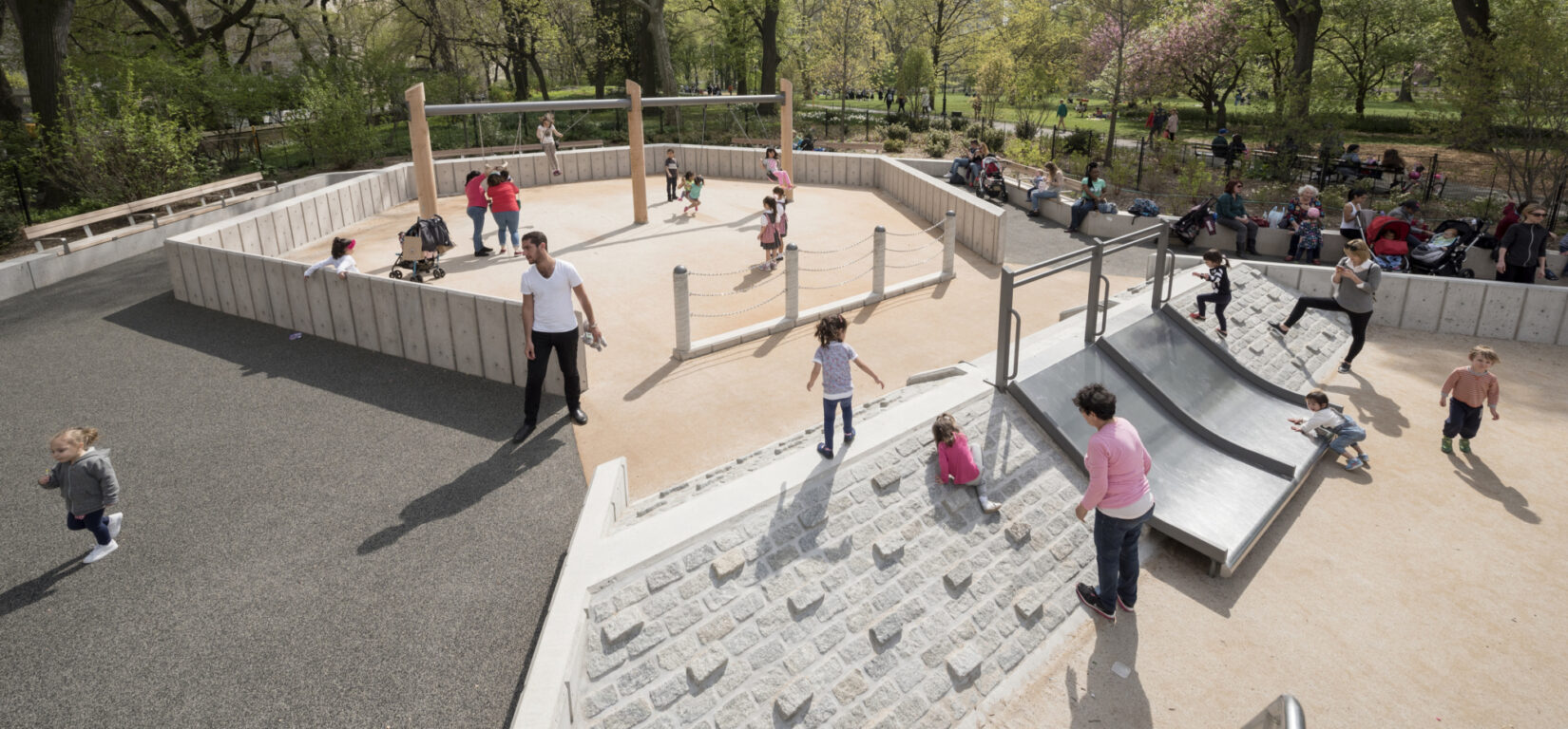 Children and caregivers enjoying the pyramid and slide in the playground