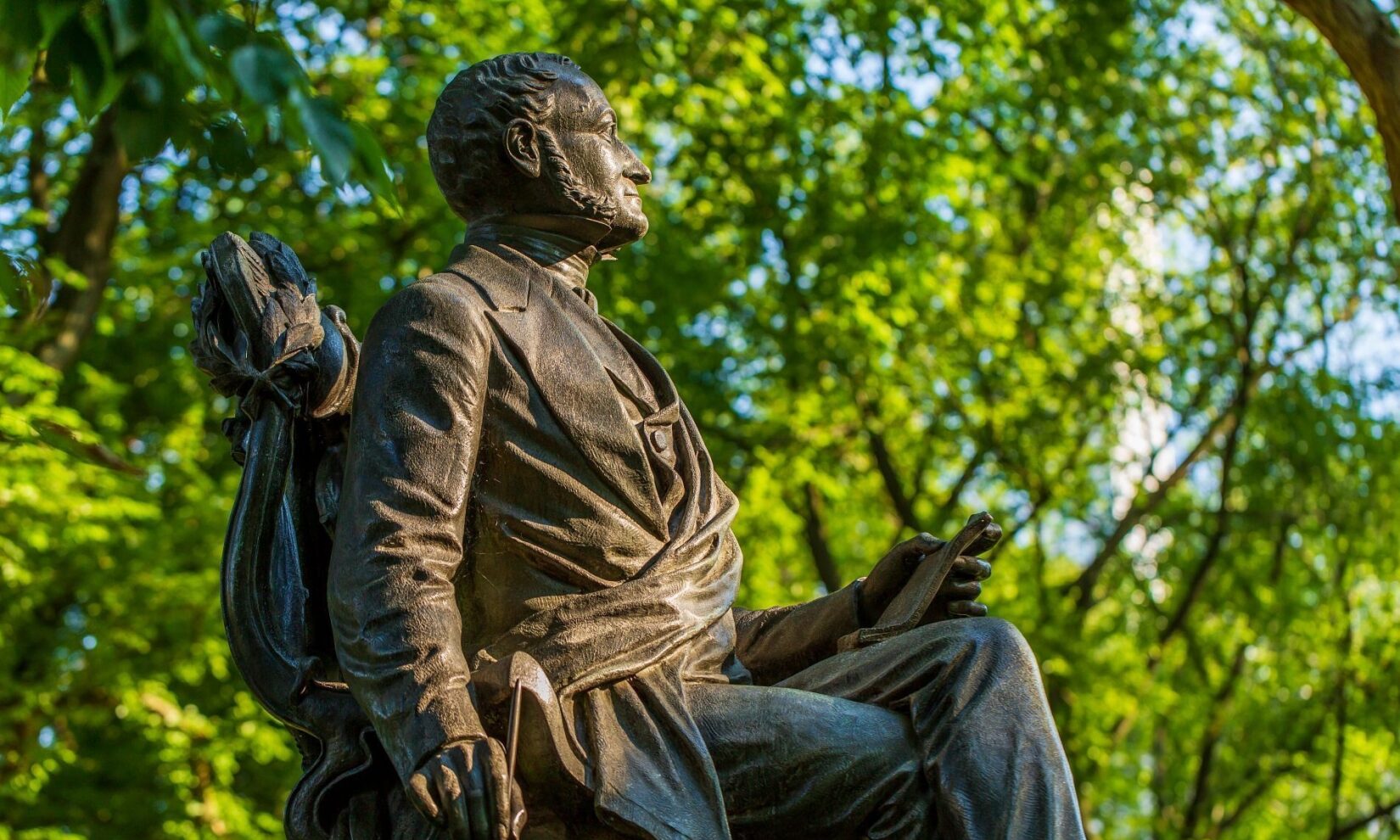 The statue is seen in profile on a summer day