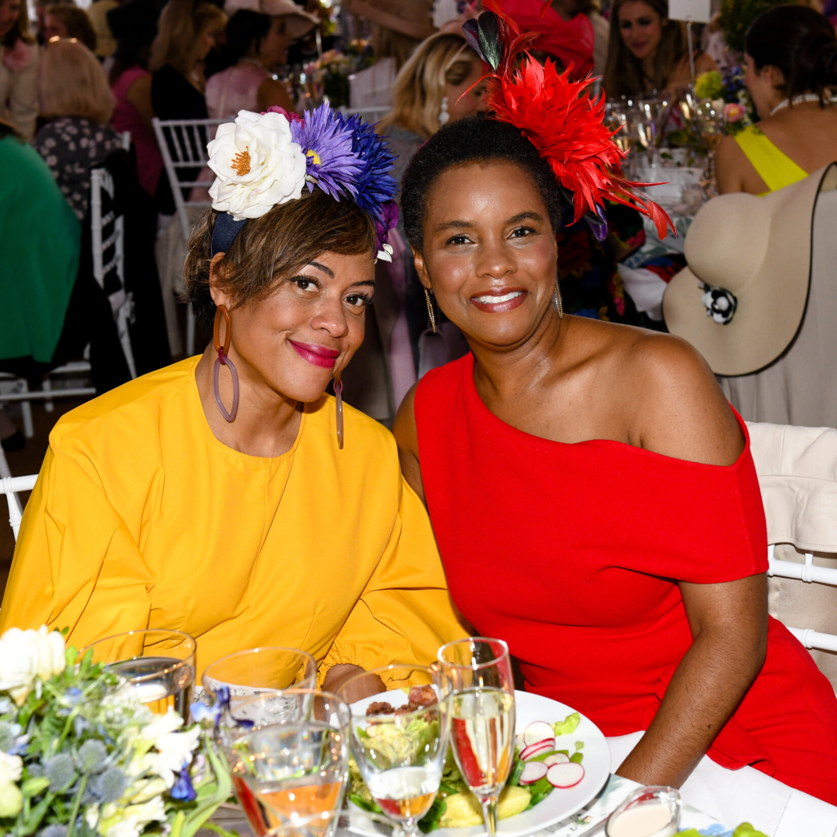 Two women sporting flowered hats enjoy the luncheon