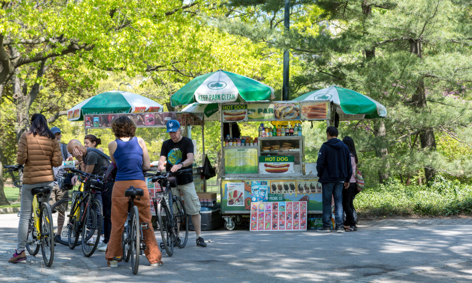 A typical Park food vendor, selling hot dogs, ice cream treats, and beverages under green and white umbrellas.