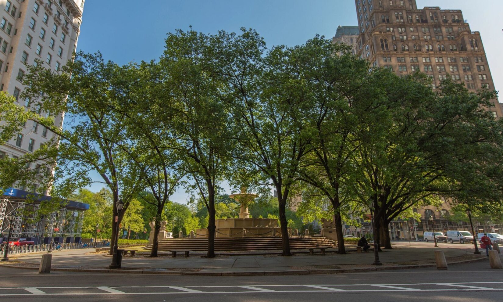 The fountain is seen surrounded by trees, with the canopy of Central Park in the background, looking north.