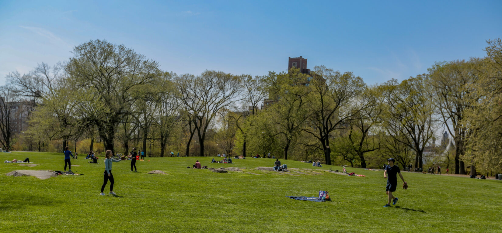 Visitors playing catch and catching rays on the Great Hill in spring