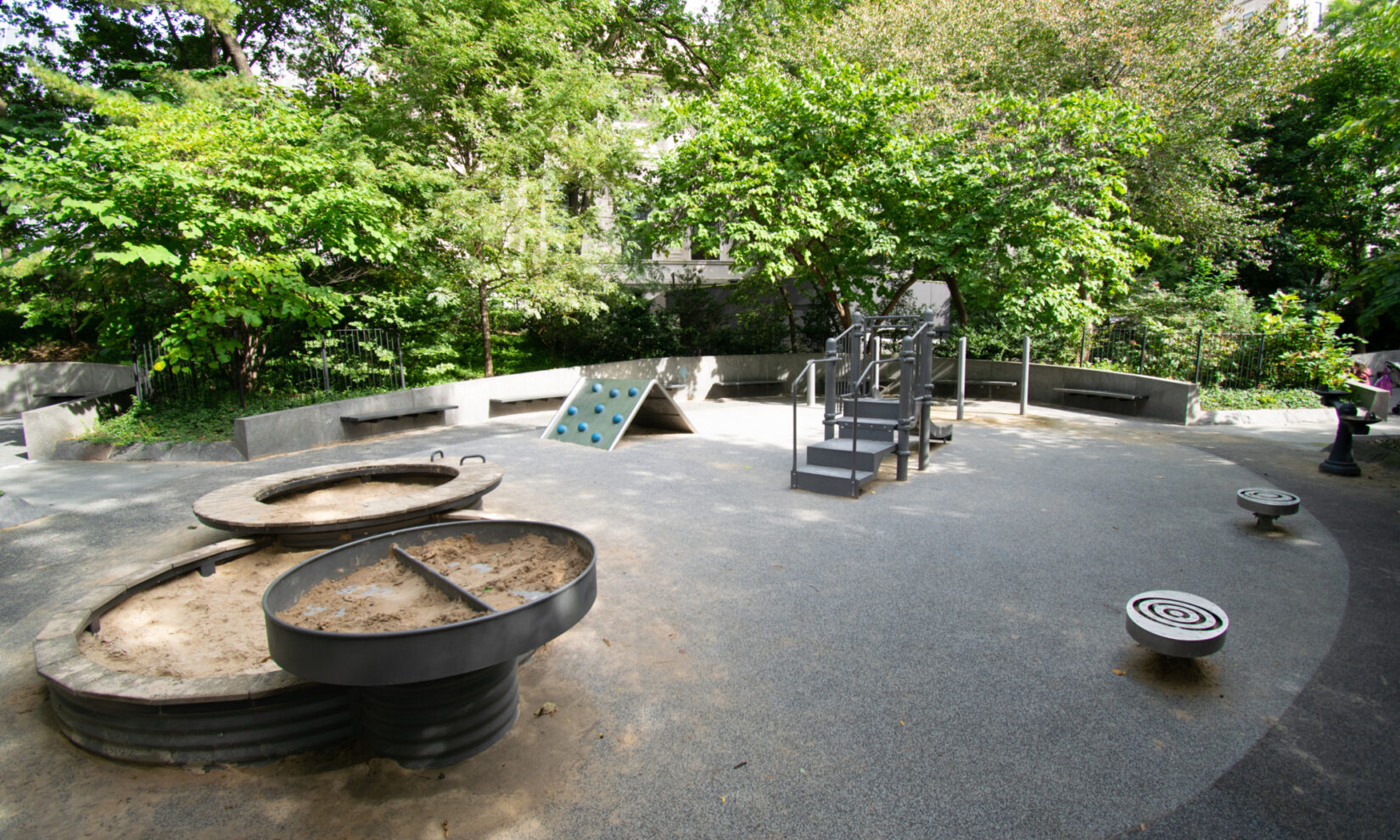 The circular play area features circular sandboxes and circular stools.