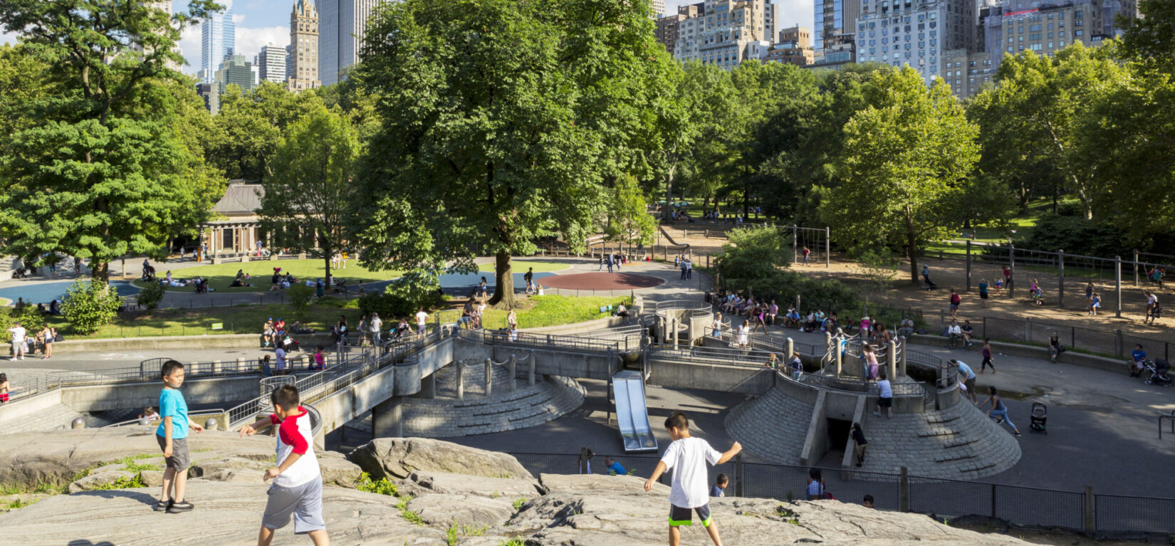 Children at play on the rocks at one end of the playground, with the skyline as a backdrop