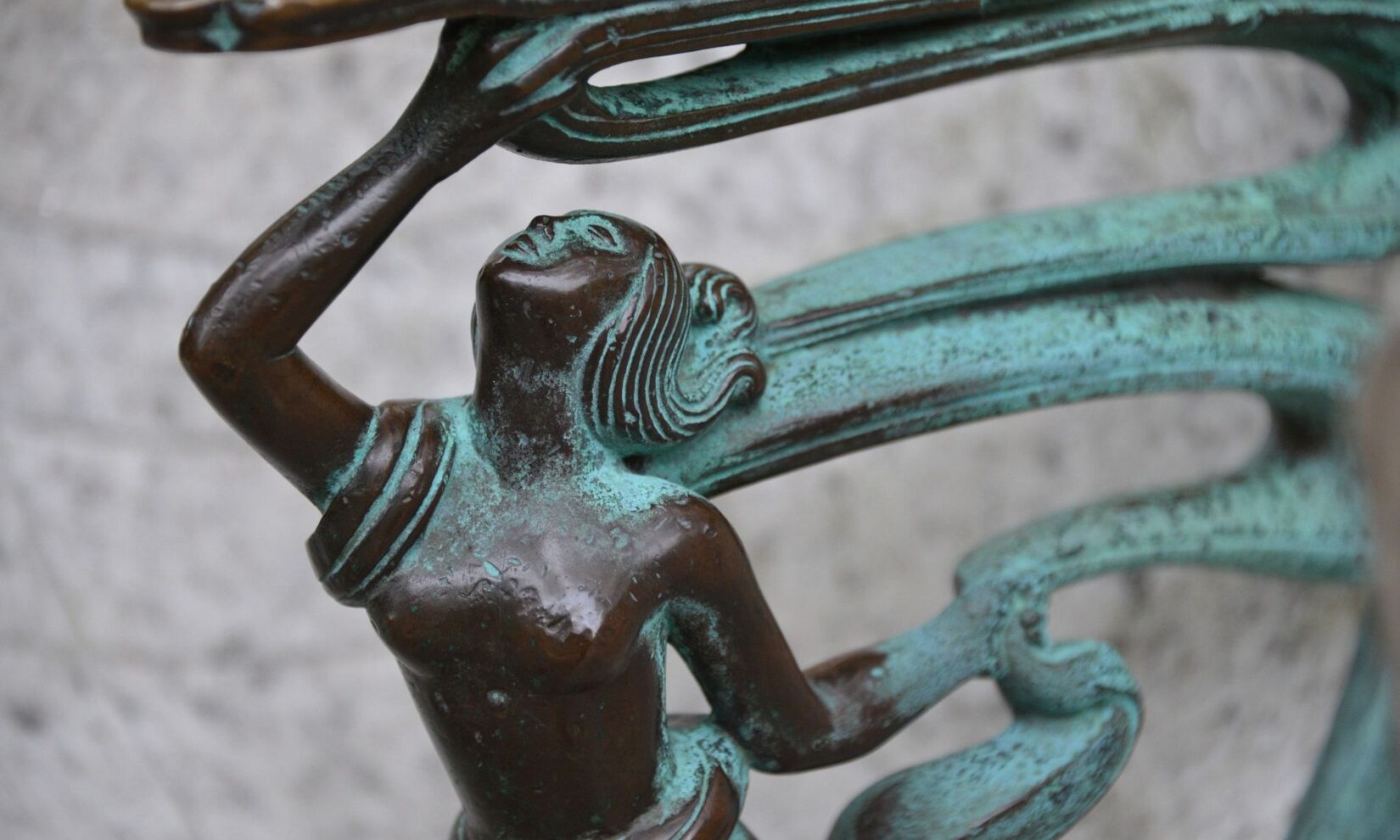 Sculptural detail of the bench shows a woman form, reaching up.