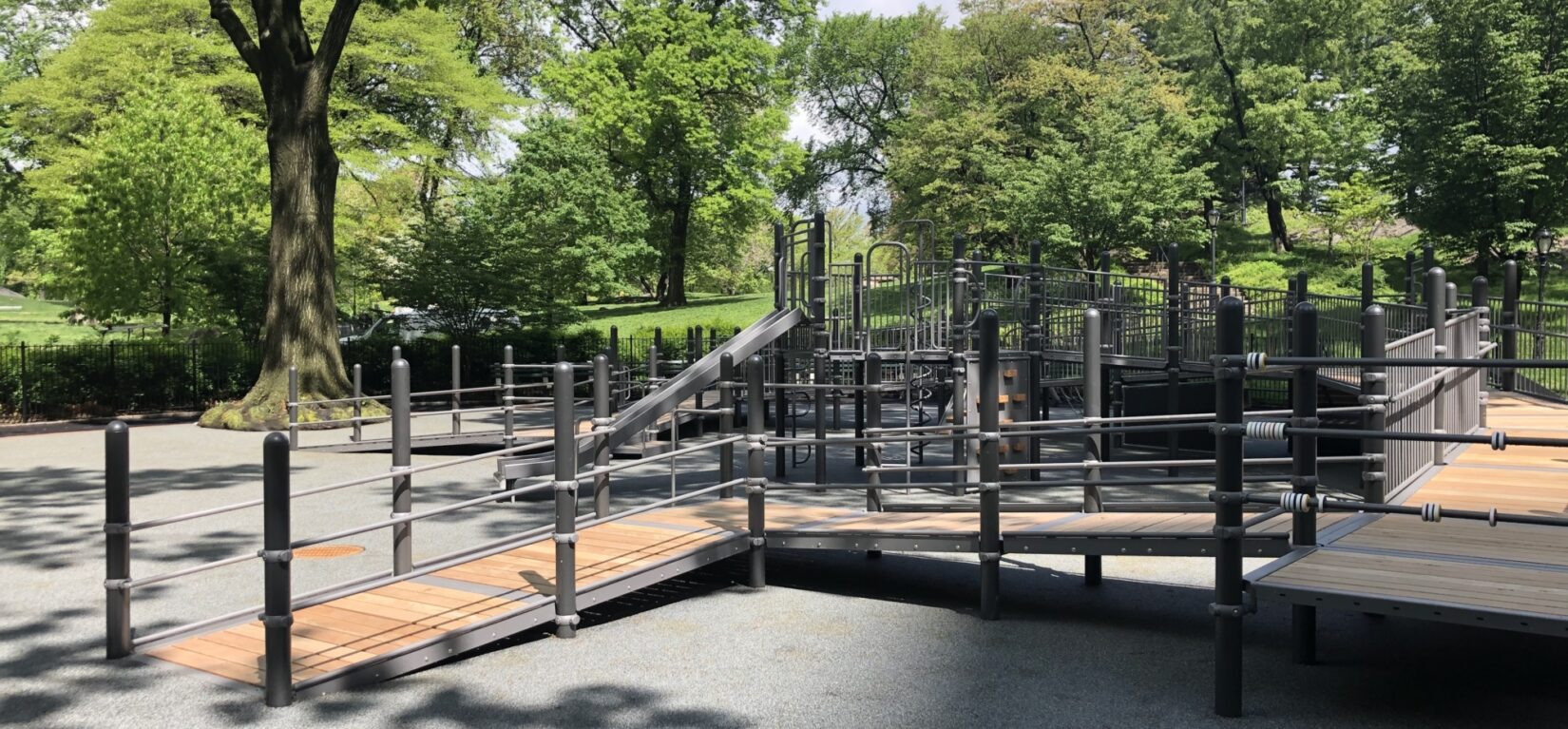 The playground is nested at the edge of a green, tree-lined landscape.