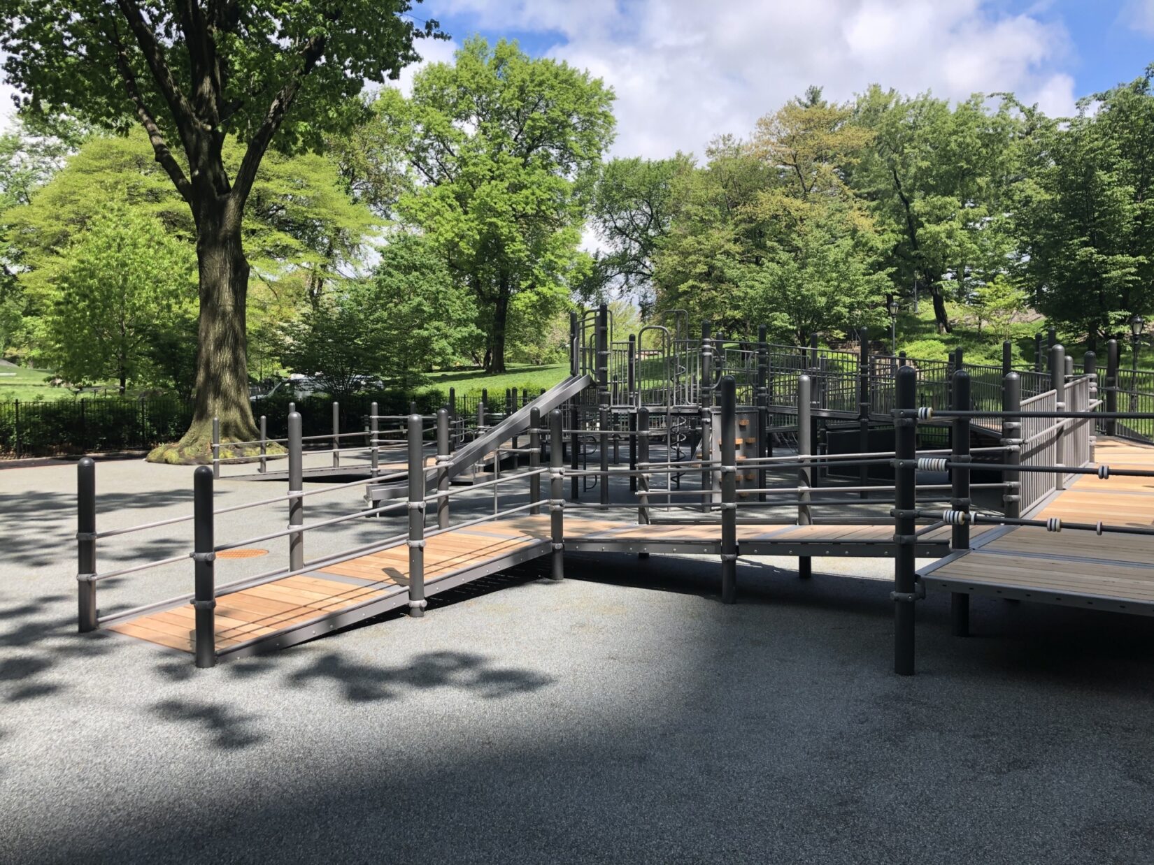 The playground is nested at the edge of a green, tree-lined landscape.