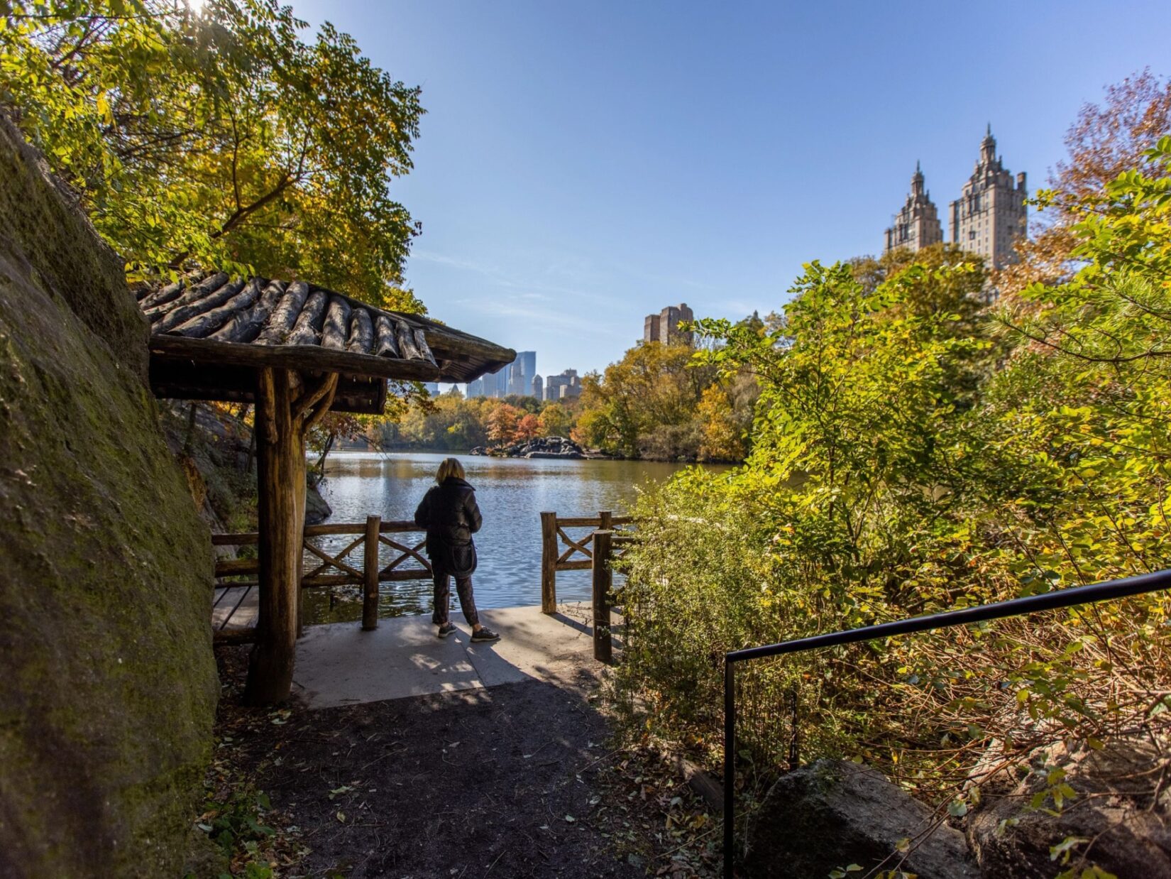 Looking down the path to the Chambers Boat Landing, where a woman looks across the Lake to the skyline at the horizon in autumn.