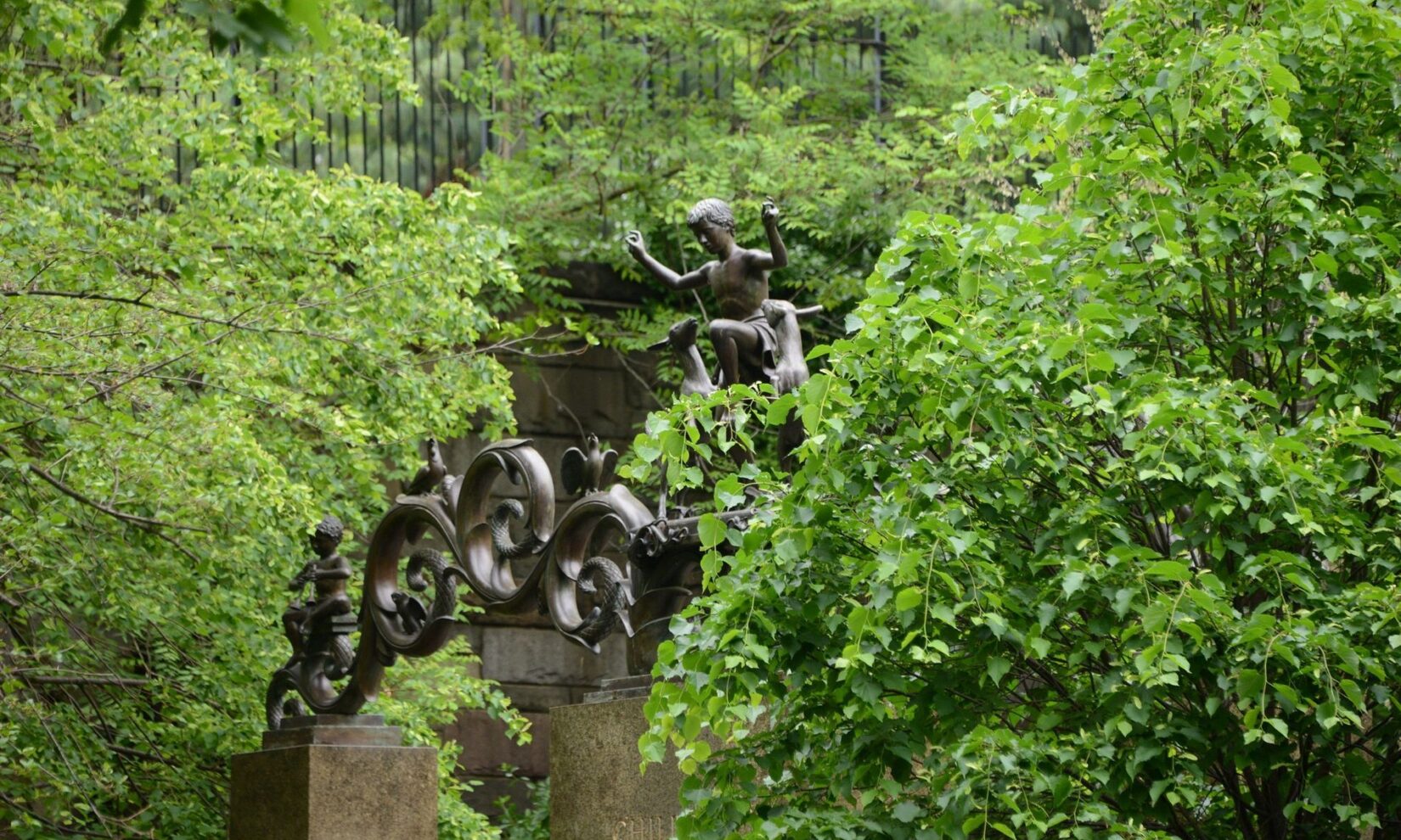 The figures at the top of the gate shown half-hidden in the neighboring tree canopy.