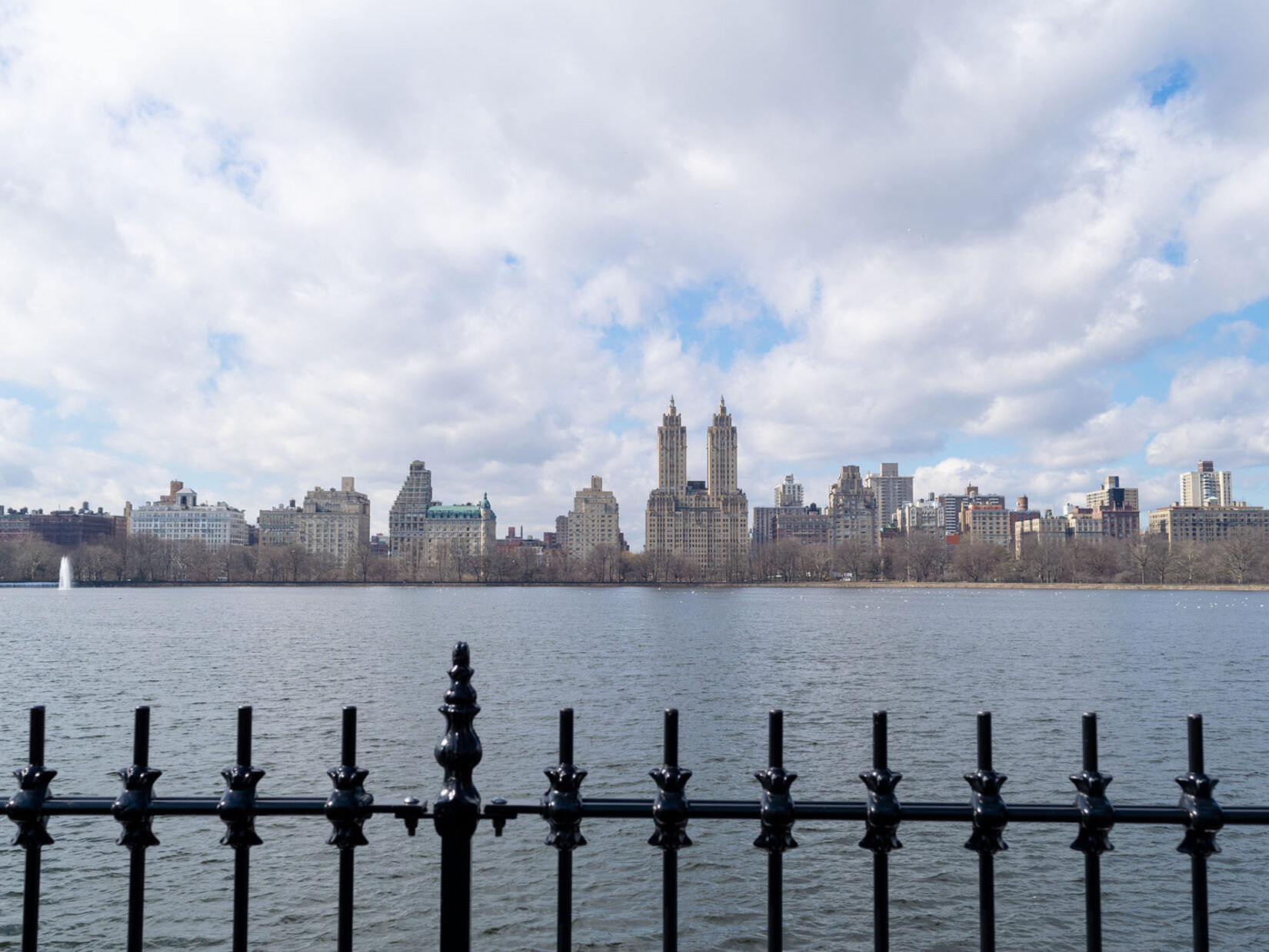 Looking across the Reservoir on a cloudy day with the ironwork of the fence in the foreground