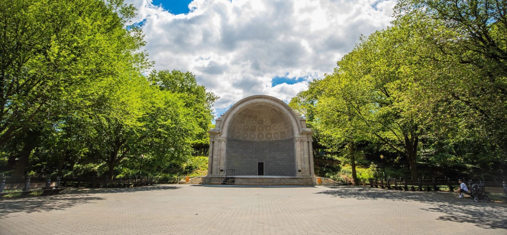 The bandshell is seen from across an empty plaza on a sunlit sping morning