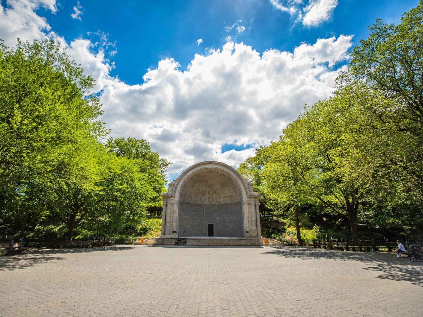 The bandshell is seen from across an empty plaza on a sunlit sping morning