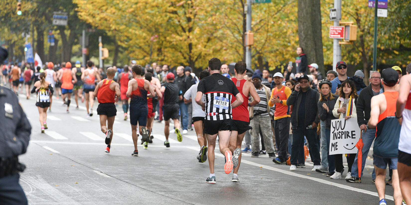 Runners pass cheering crowds lining a roadway in the Park