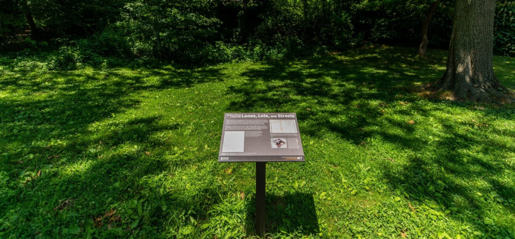 An example of the interpretive signage stands in the landscape of Seneca Village