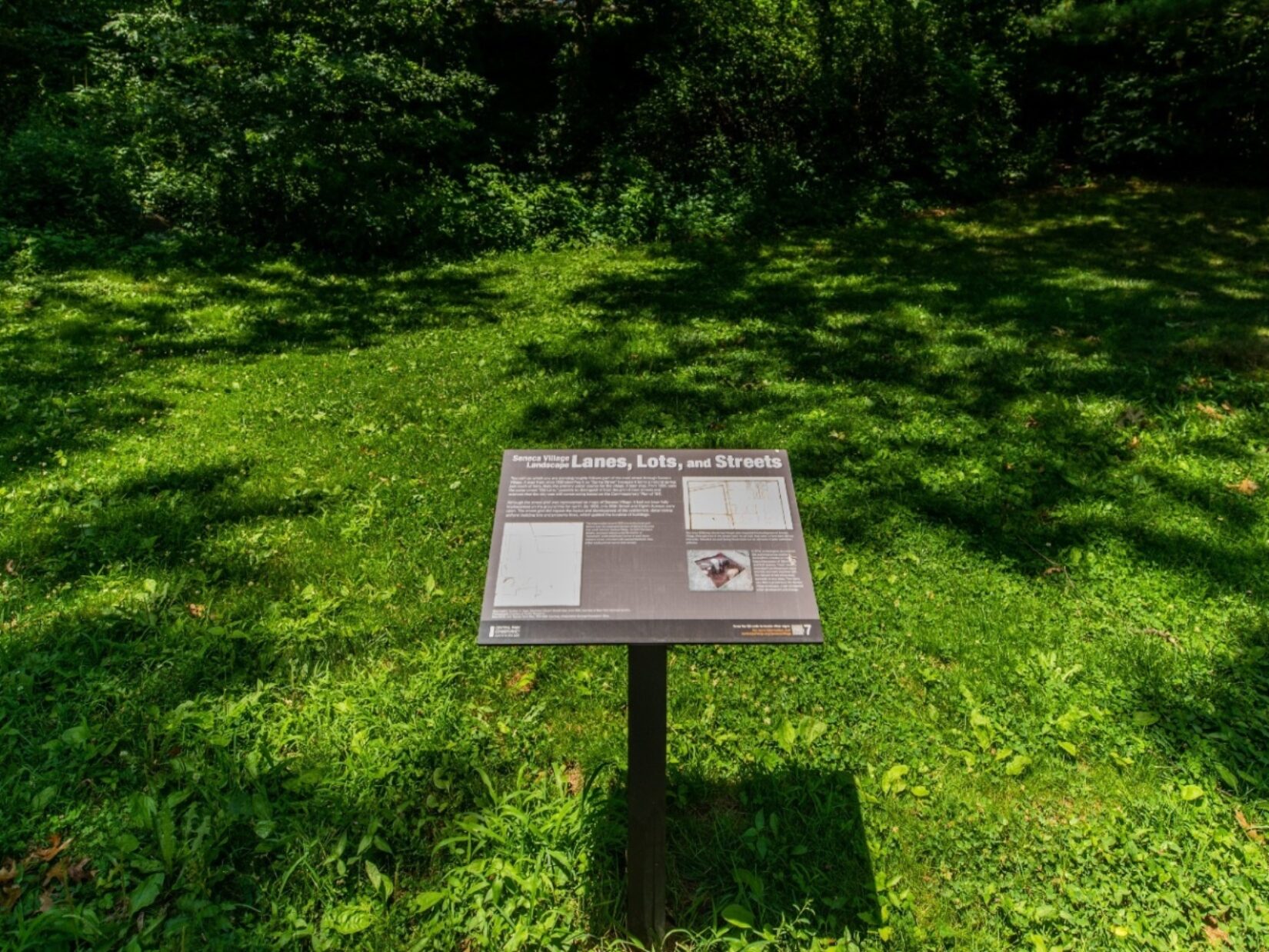 An example of the interpretive signage stands in the landscape of Seneca Village