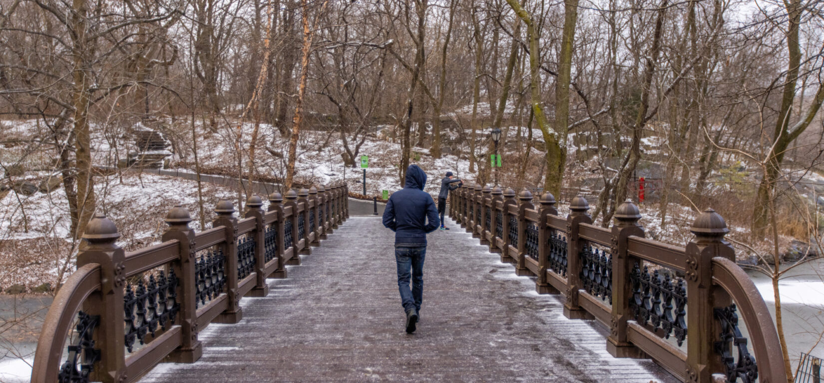 A person walks over a snowy bridge.